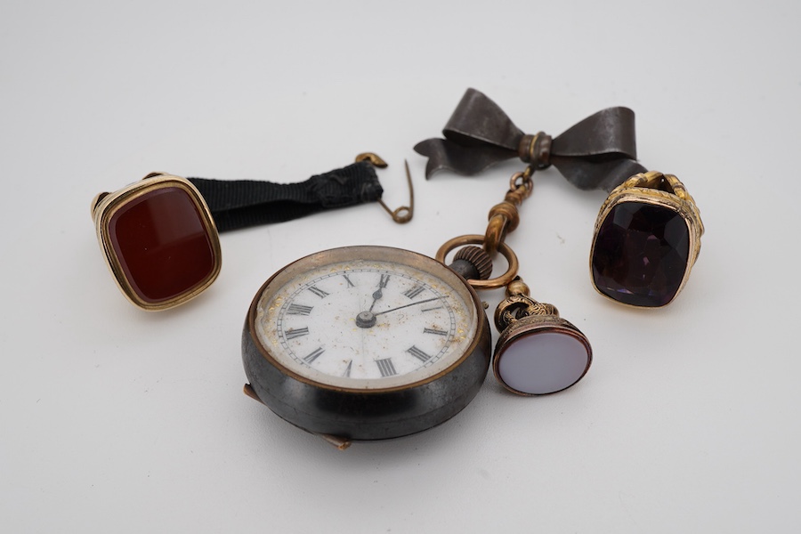 Three assorted yellow metal overlaid and gem set fob seals, including carnelian, largest 26mm, together with a gun metal fob watch, with yellow metal inset plaque.